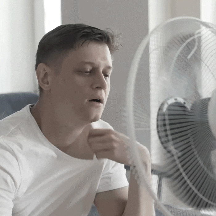 Person feeling overheated in front of a traditional fan