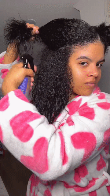 Woman applying hair spray to her hair